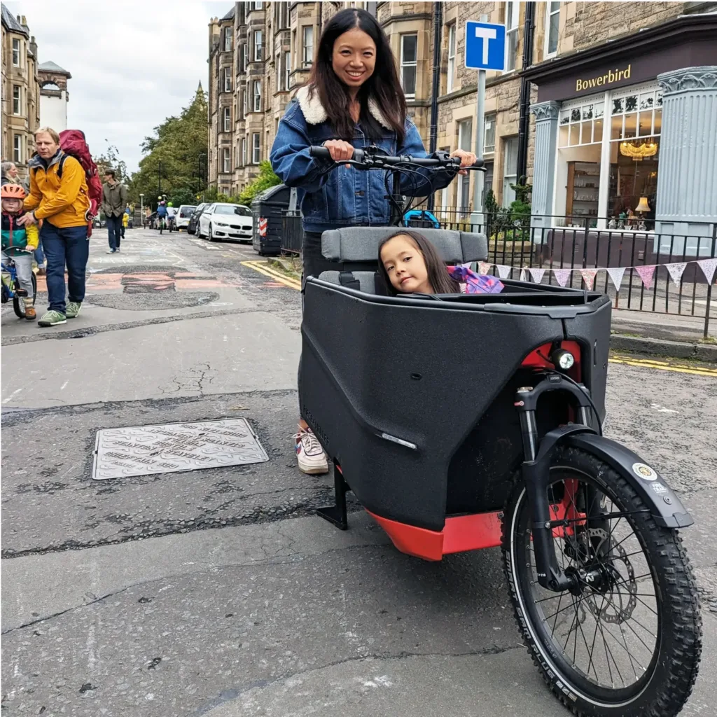 Young woman setting off on cargo bike with child in the cargo seat
